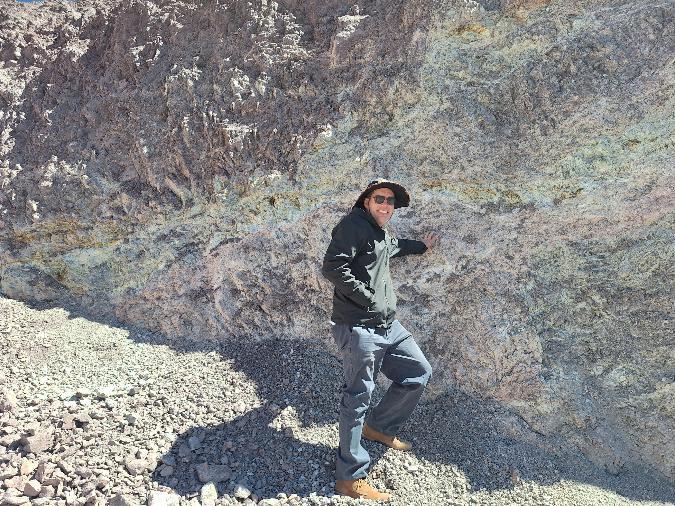 Geologist standing at an altered rock face at Calaboso Prospect